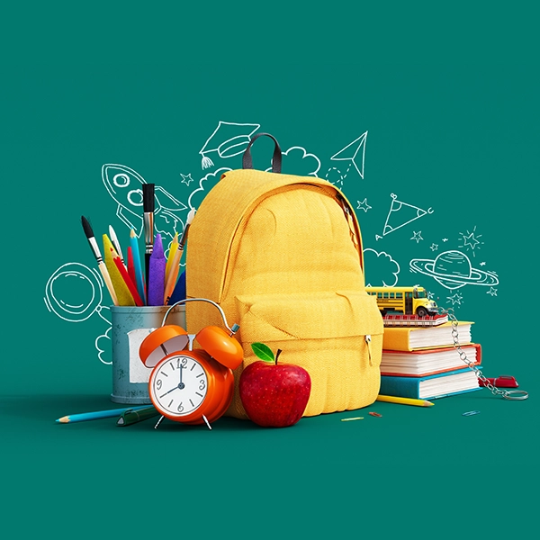 Gelber Rucksack mit Schulmaterialien auf grünem Hintergrund